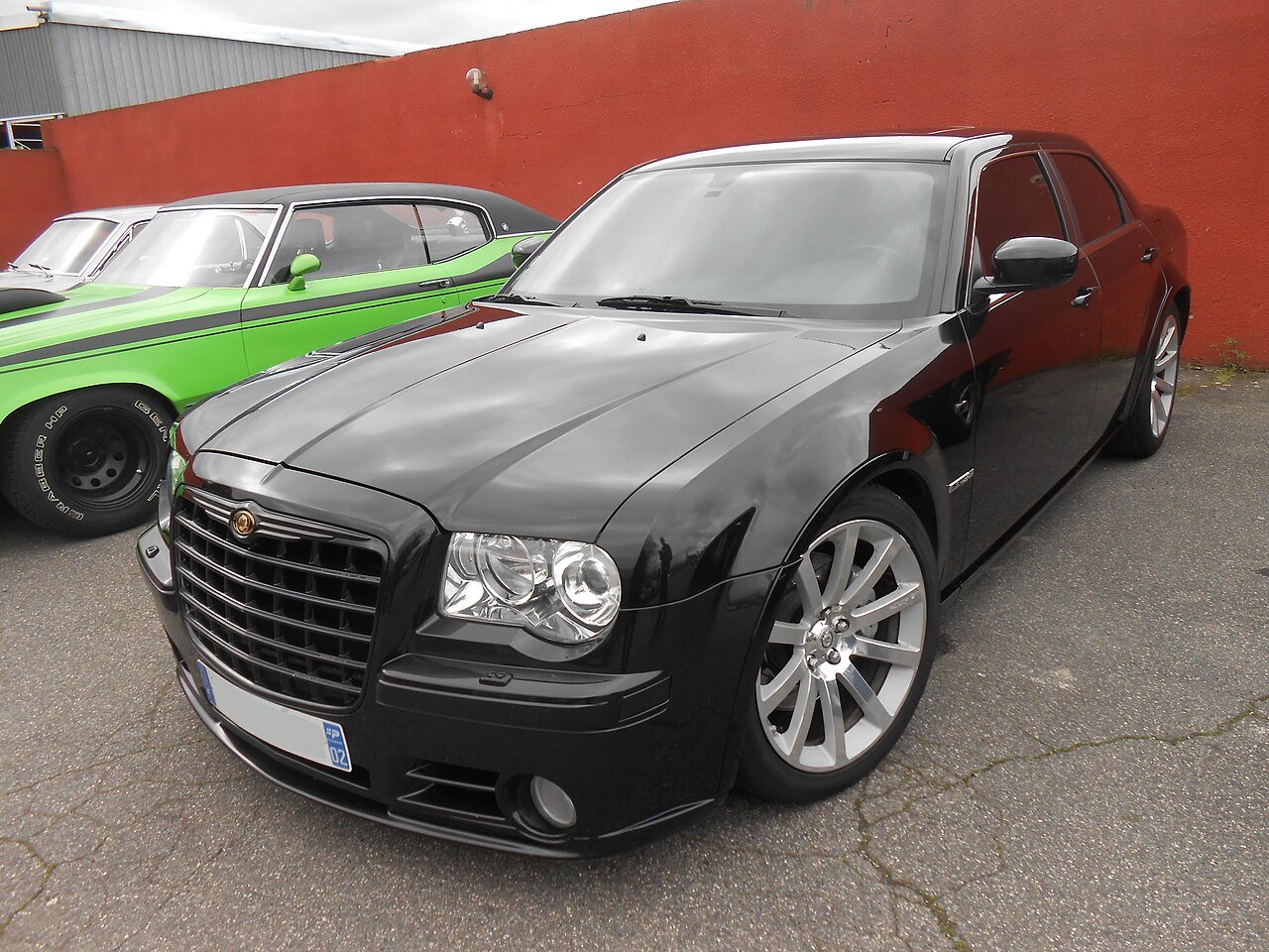 First-generation black Chrysler 300C SRT8 parked next to a classic muscle car