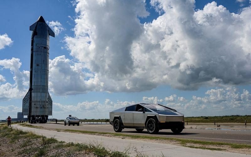 A Cybertruck with a Starship in the background