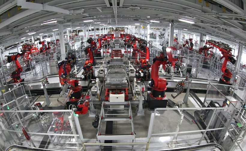 Tesla assembly line robot arm working on a vehicle body