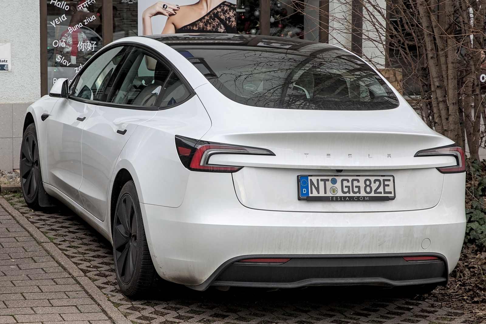 White Tesla Model 3 front three-quarter view in a parking garage